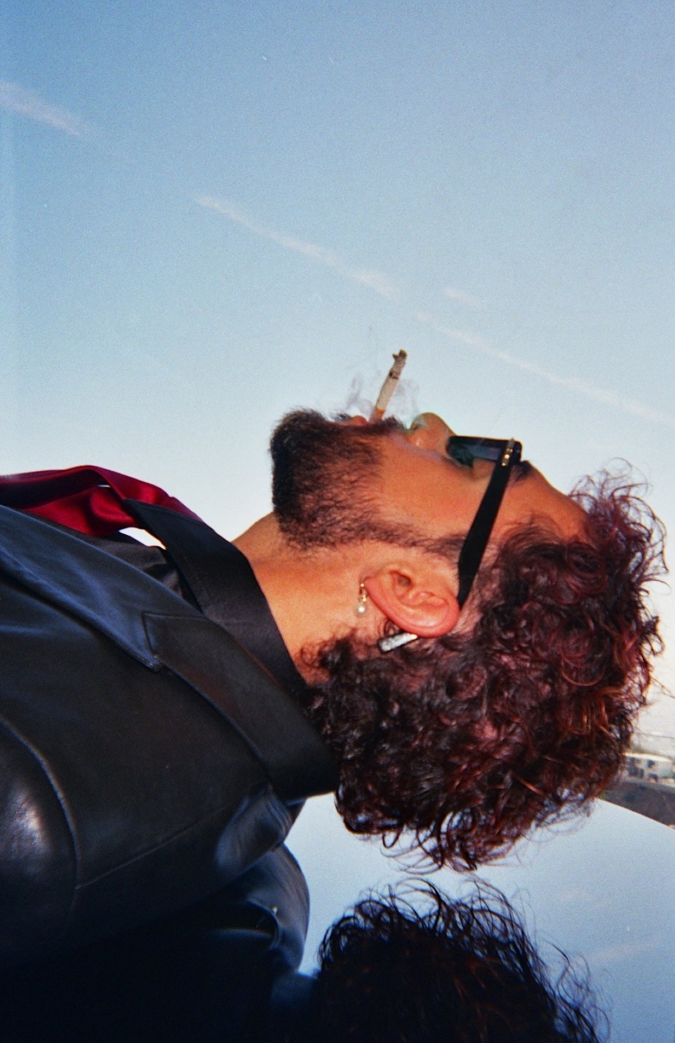 Sofiane Pamart renversé sur son piano face au ciel, cigarette et lunettes noires