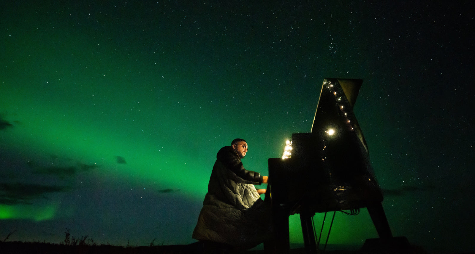 Sofiane Pamart au piano à queue sous les aurores boréales, lors de son live Cercle