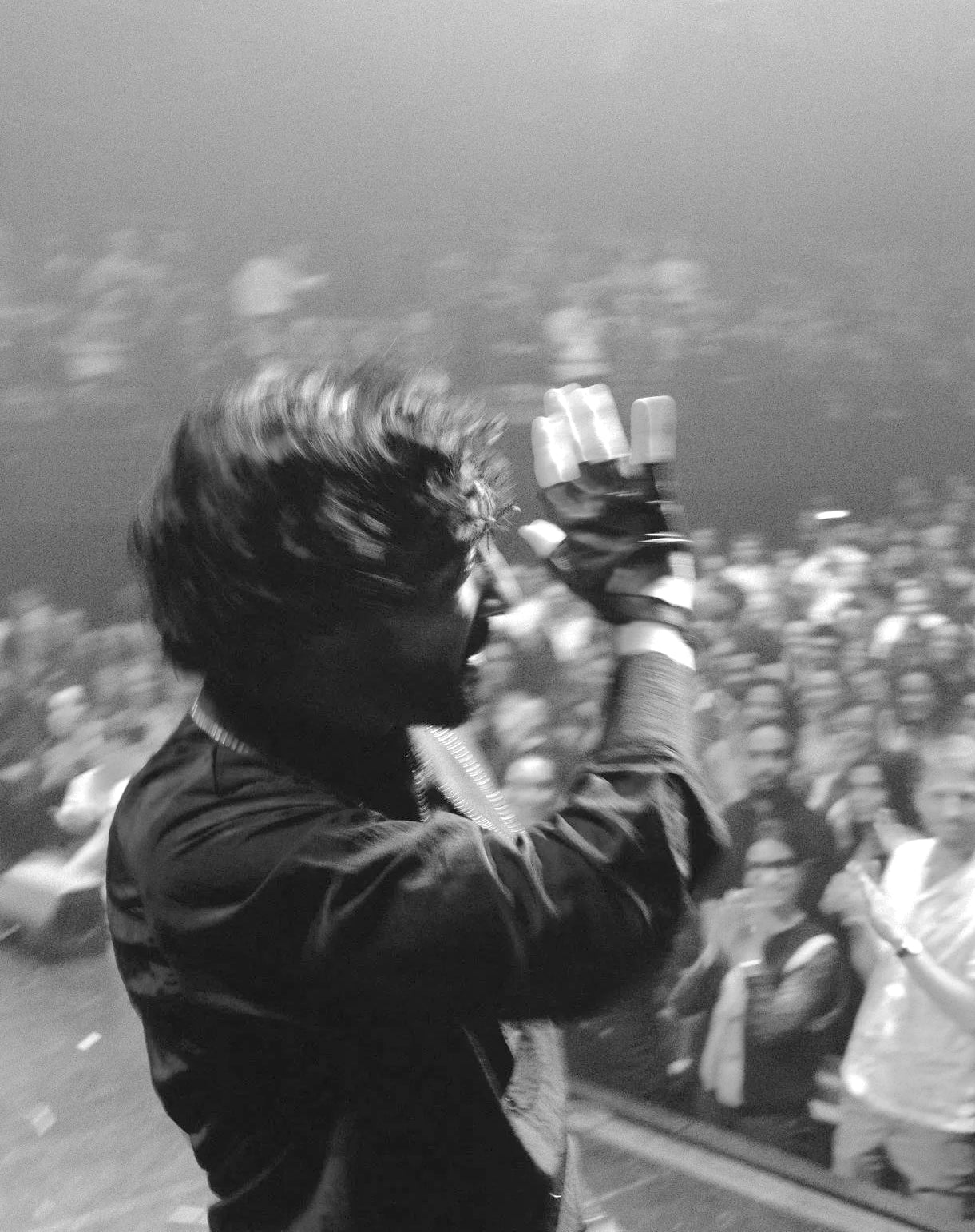 Sofiane Pamart levant la main vers son public, en noir et blanc
