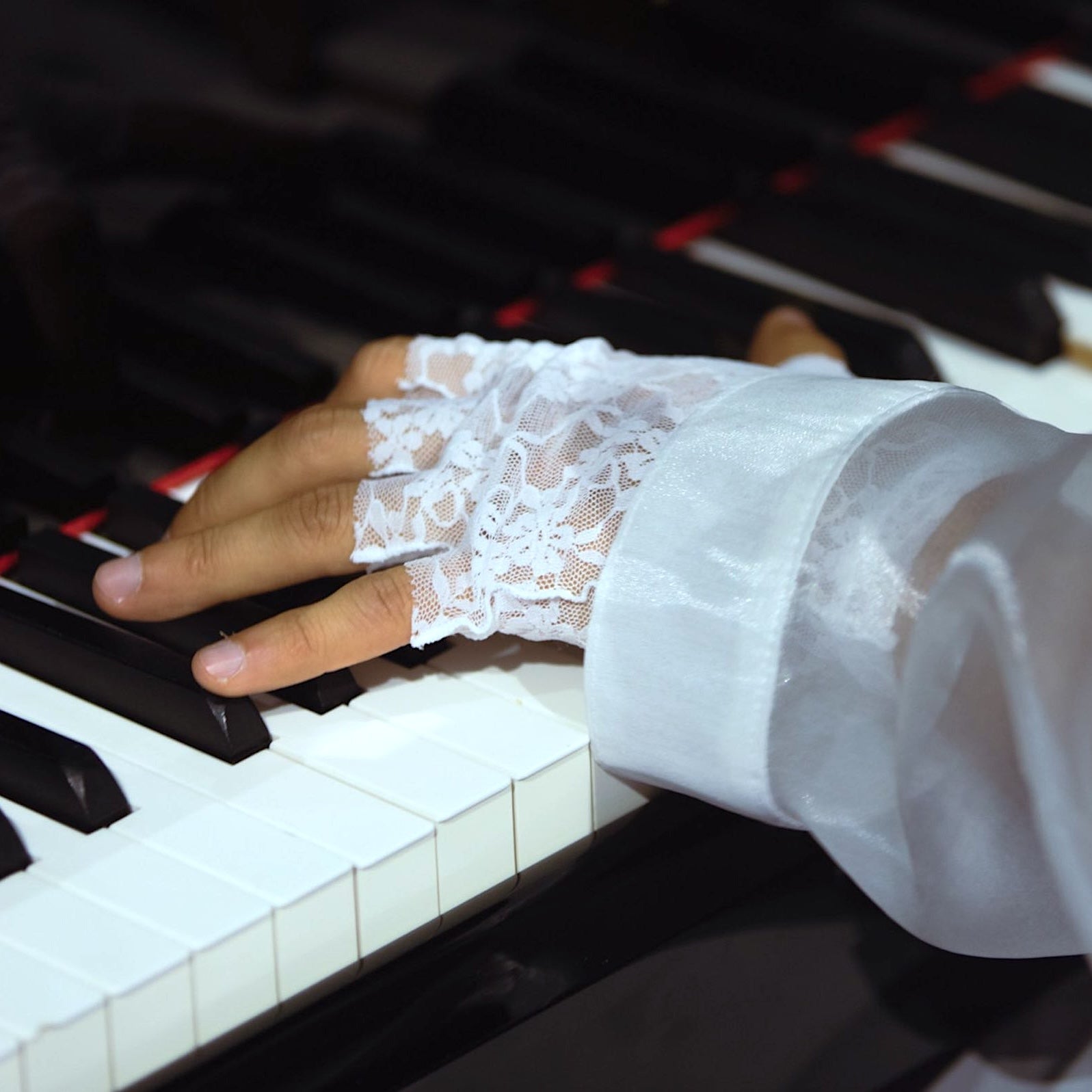 Les mains de Sofiane Pamart sur les touches du piano, manchette en dentelle