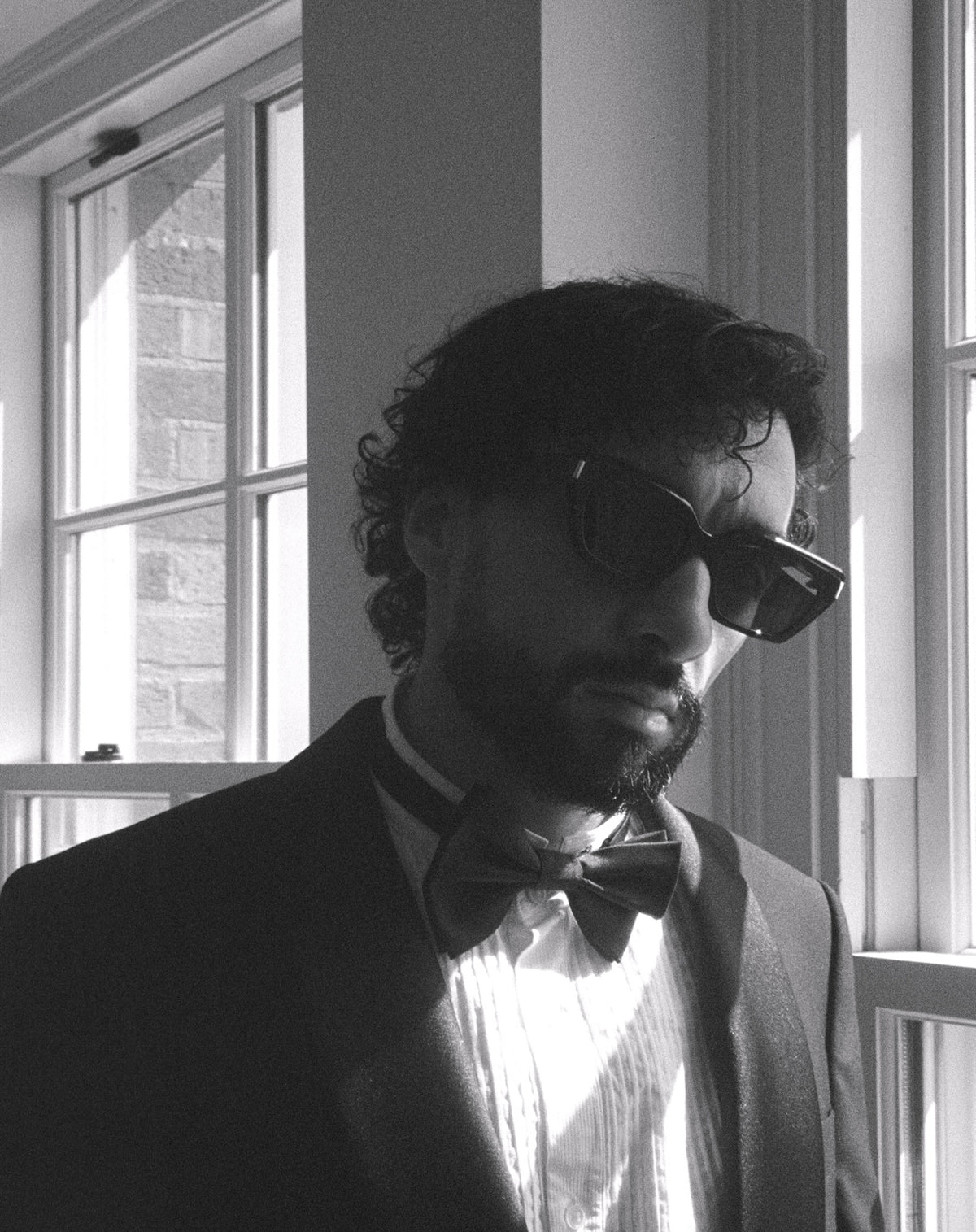 Sofiane Pamart en smoking et nœud papillon près d’une fenêtre, portrait noir et blanc